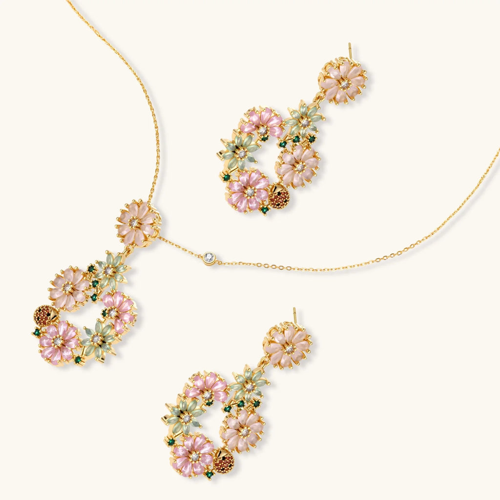 14K gold plated jewelry set with pink and green cubic zirconia flowers arranged in wreath design on cream background