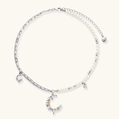 Silver-toned crescent moon pendant with star accents on pearl and chain necklace against white background.