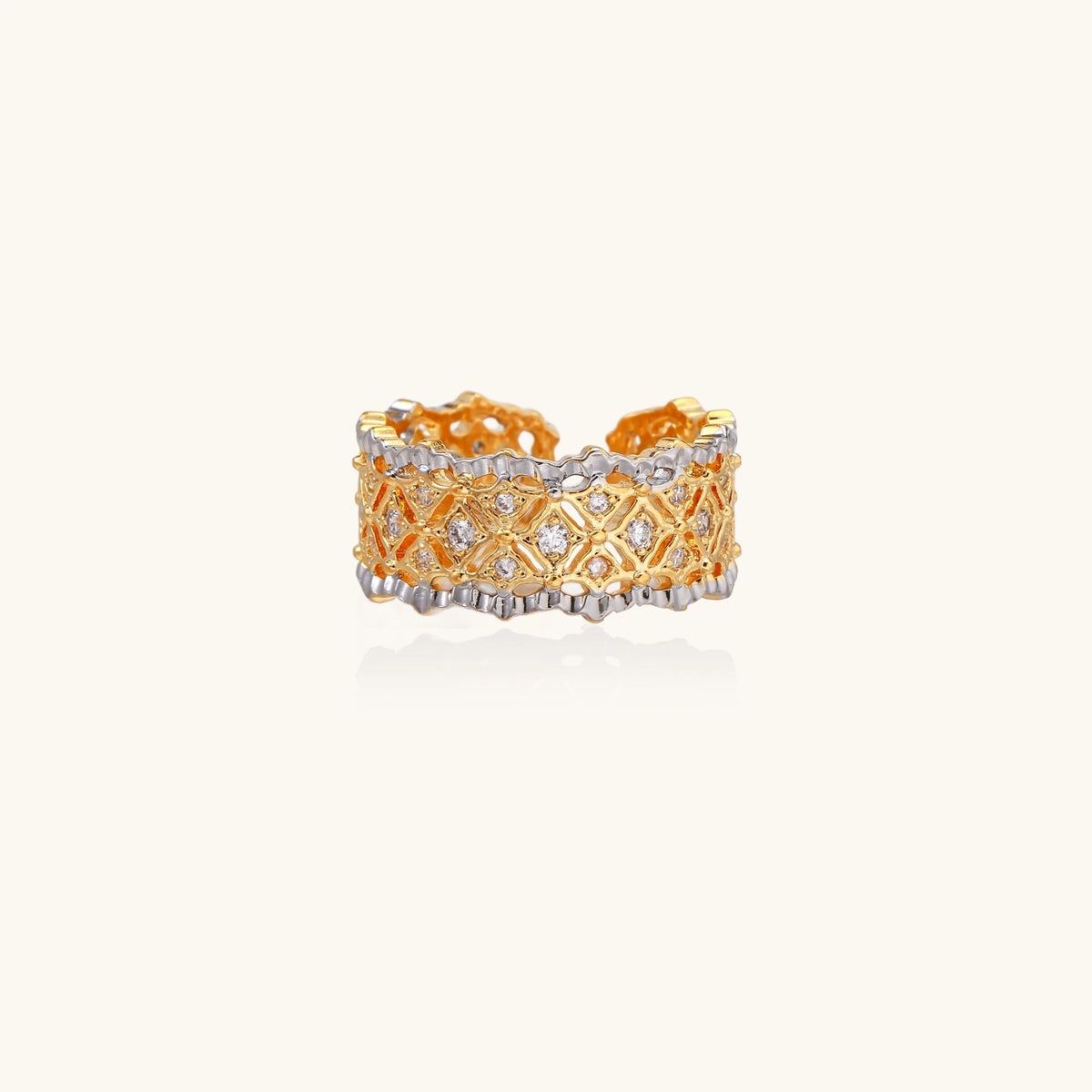 Two-tone ring with geometric lattice pattern in gold and silver finish with crystal accents on beige background