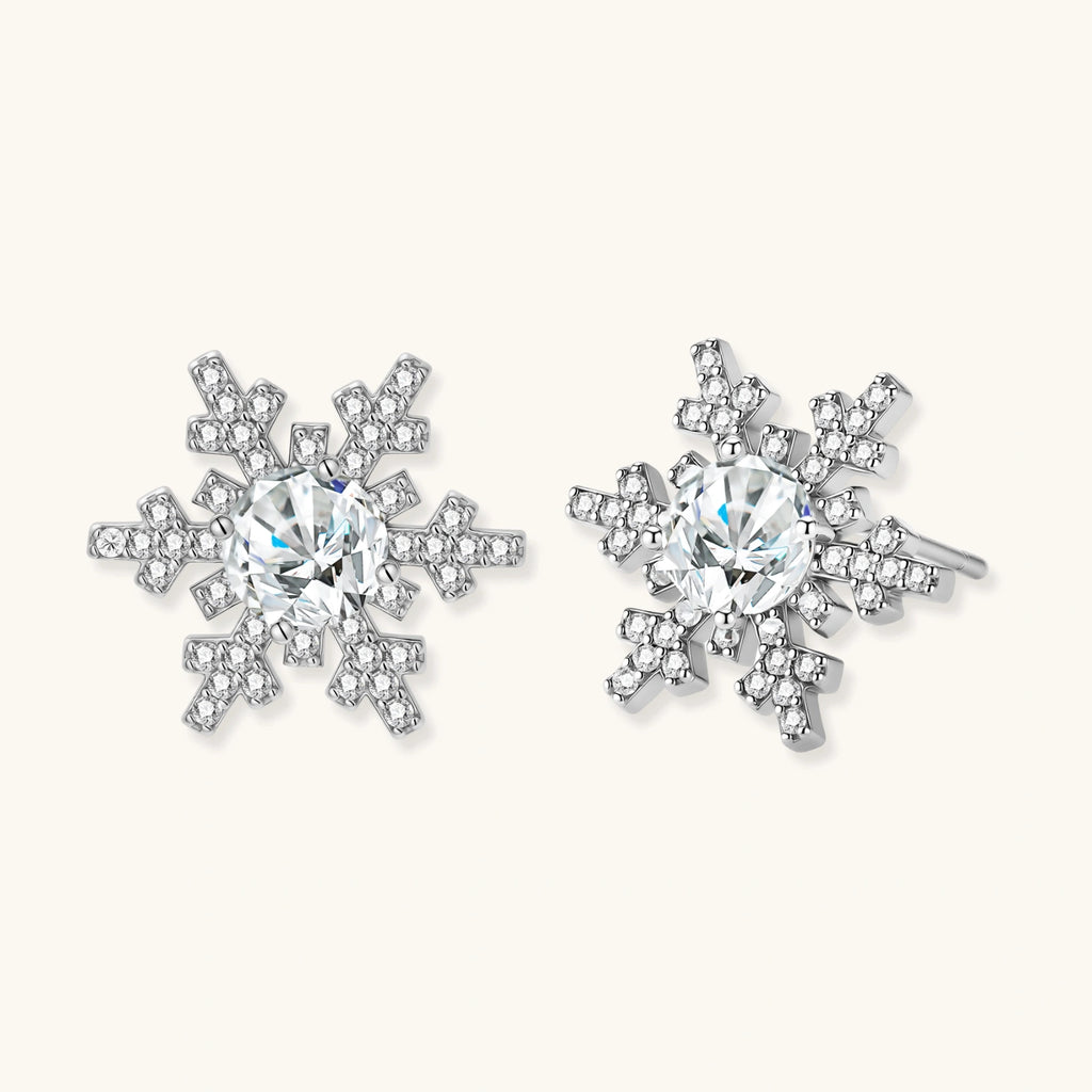 Sterling silver snowflake stud earrings with brilliant moissanite centers and intricate geometric patterns on cream background
