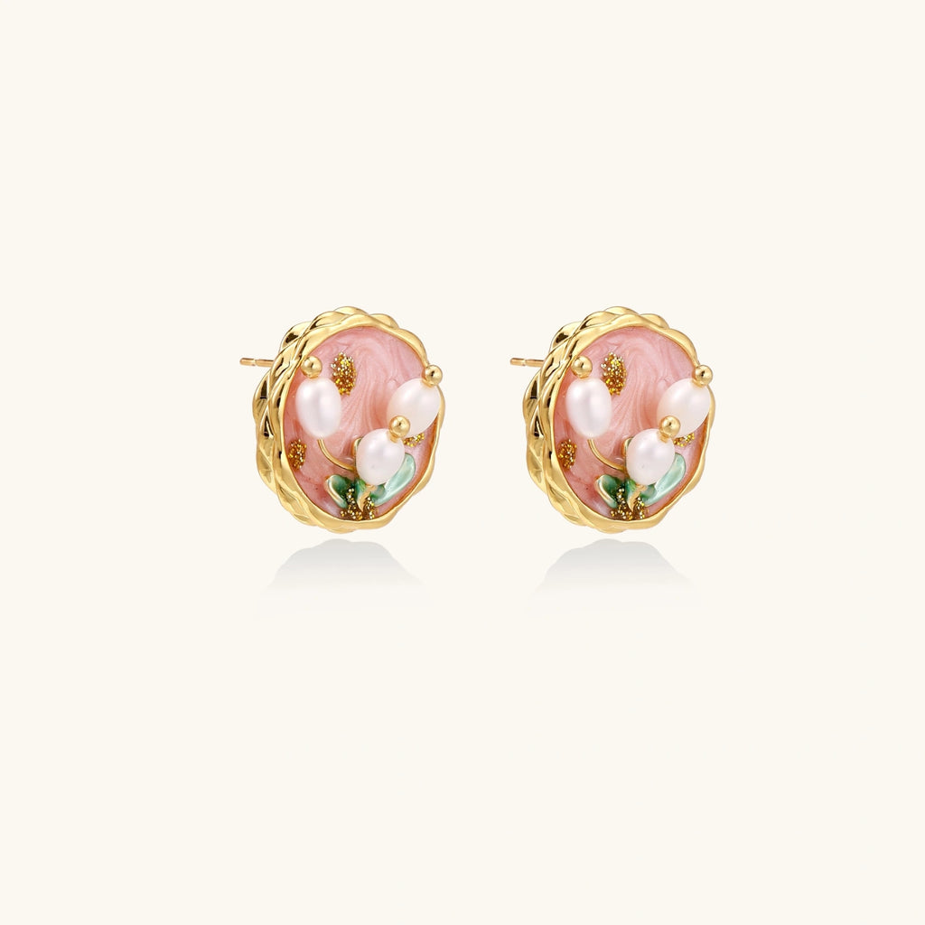 Round stud earrings with pink enamel, three white freshwater pearls, green leaves, and gold-plated braided border