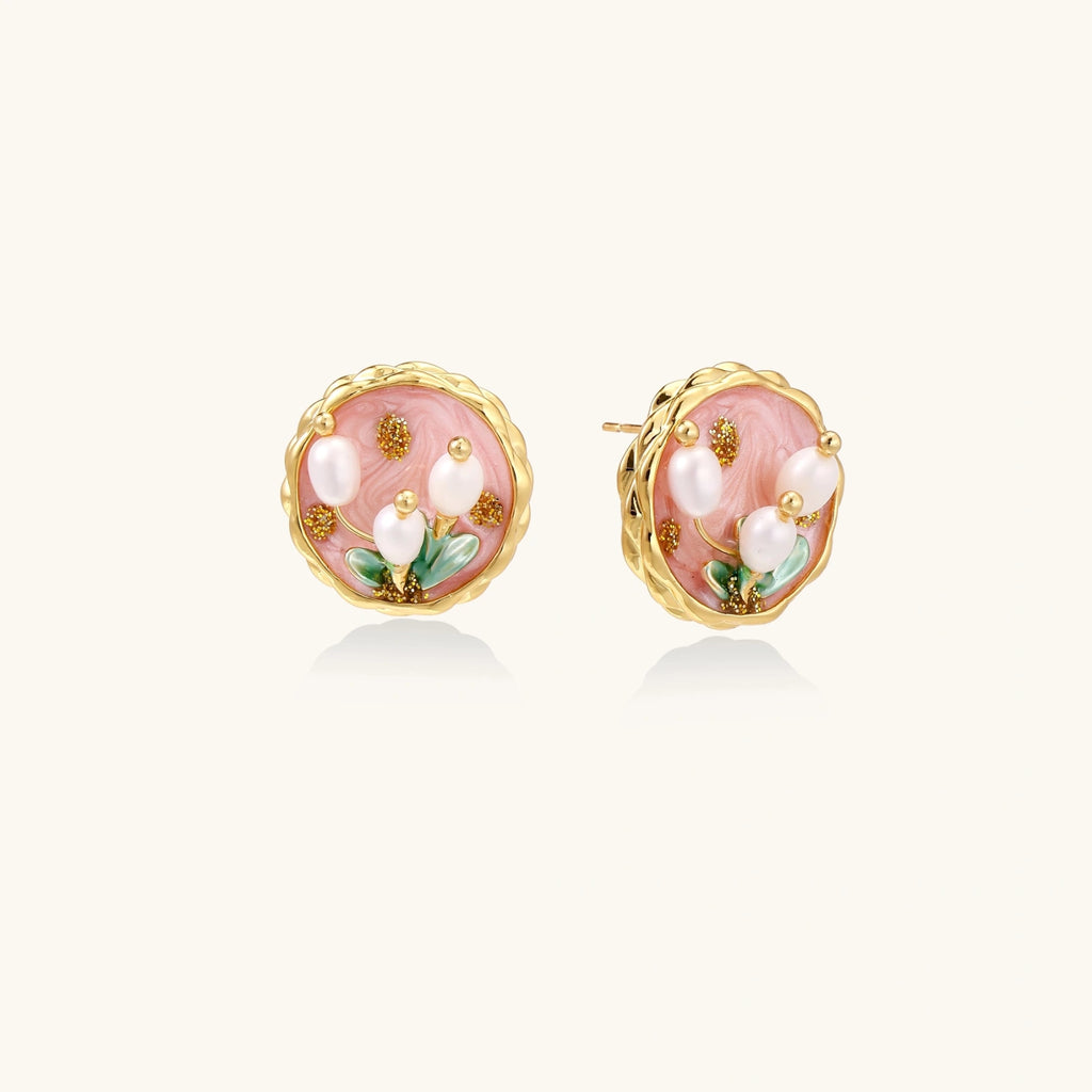 Round stud earrings with pink enamel, three white freshwater pearls, green leaves, and gold-plated braided border