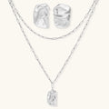 Modern textured hoop earrings and layered chain necklace with liquid metal pendant in silver and gold finishes.