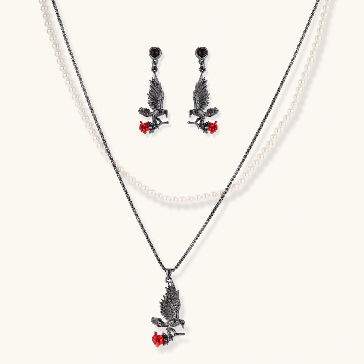 Dark gunmetal jewelry set featuring detailed raven pendants carrying red enamel roses with layered pearl and chain necklaces