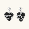 Pair of black heart drop earrings in ebony wood with silver-tone thorny vines, zirconia stones and round ball studs on cream background.
