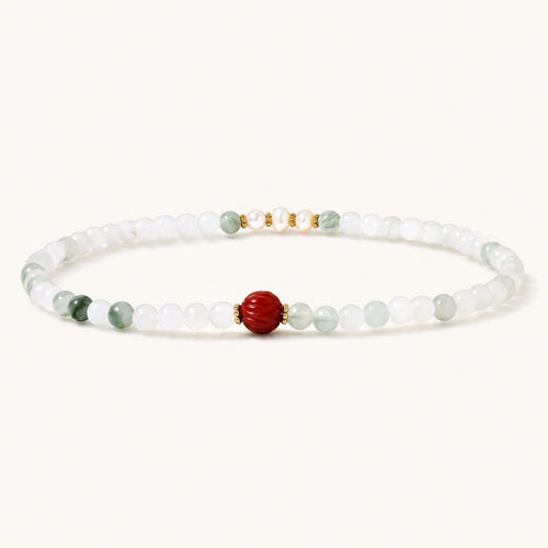 Three layered white beaded bracelets with carved orange agate lotus centerpiece and freshwater pearls on cream background.